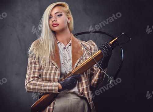 Preview: Studio portrait of blond old fashioned female holds a crossbow.