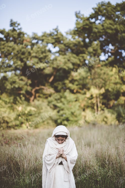Preview: Vertical shot of a female praying while wearing a biblical robe