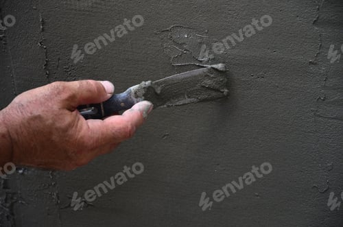 Preview: Hands of an old manual worker with wall plastering tools renovating house