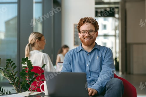 Preview: Handsome entrepreneur working on laptop sitting in modern coworking during working day