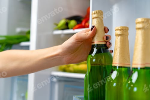 Preview: Female hand taking bottle of beer from a fridge
