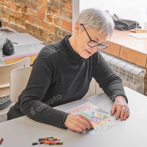 Preview: Senior woman creating drawing of flowers with pastel crayons at creative workshop