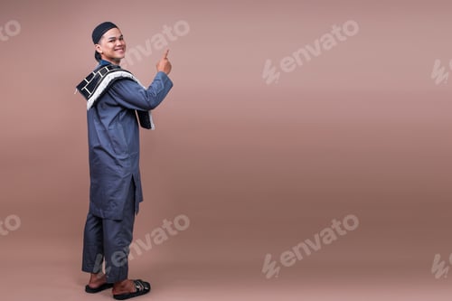 Preview: Full Body Of Smiling Young Muslim Man Standing On Beige Background And Pointing To Ads Space