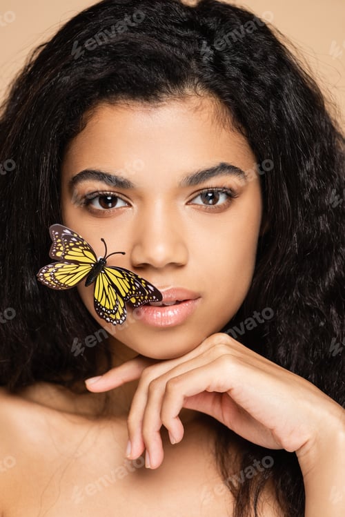 Preview: brunette african american woman with decorative butterfly on face looking at camera isolated on