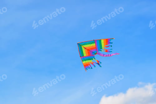 Preview: Rainbow kite flying high in blue sky, viewed from below. Symbol of freedom, rainbow, happiness