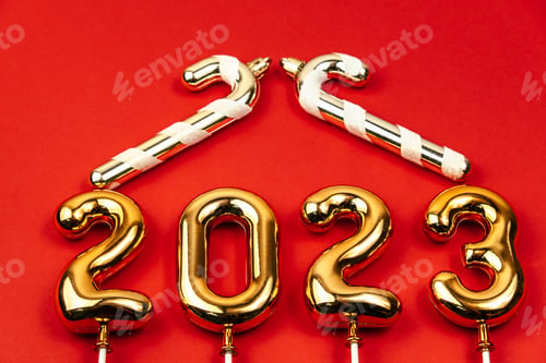 Preview: festive red background with gold numbers 2023 and gold decorative candy canes in form of house roof.