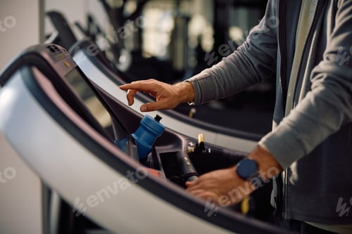 Preview: Close up of athlete adjusting speed on treadmill in a gym.