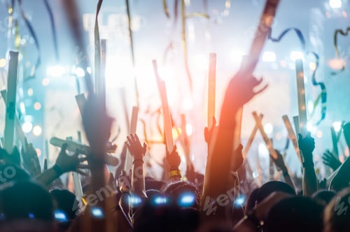 Preview: silhouettes of hand in concert.Light from the stage.confetti.the crowd of people silhouettes with th