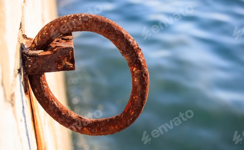 Preview: Rusty bollard waits at quay for a boat to be tied. Blur sea for background, closeup, details, banner
