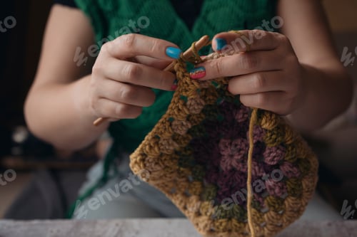 Preview: wonan's hands crocheting multicolored granny square at home