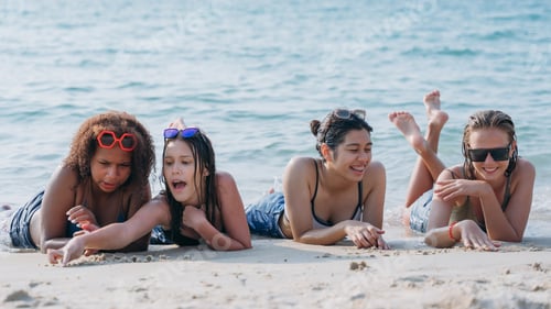 Preview: Teenagers laughing and playing in the sea with colorful swim rings, enjoying youthful summer fun.
