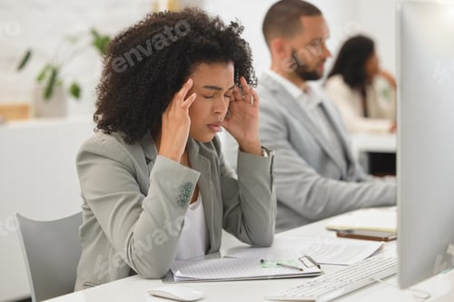 Preview: Young mixed race businesswoman suffering from a headache while working on a desktop computer in an