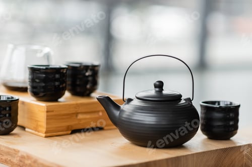 Preview: traditional Chinese teapot near cups and glass jug with puer tea on blurred background