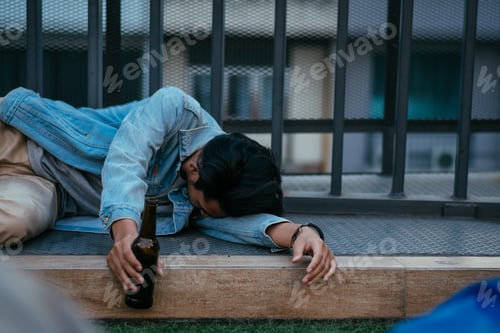 Preview: Asian sleepy drunk man holding beer bottle and lying on floor after party