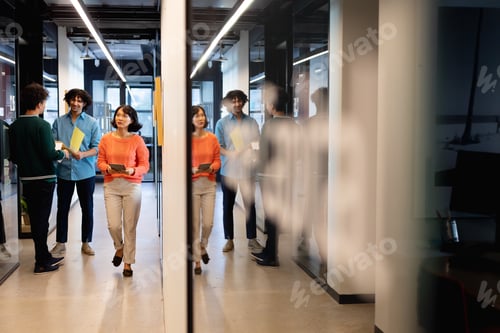 Preview: Multiracial colleagues discussing while businesswoman walking with tablet pc in corridor at office