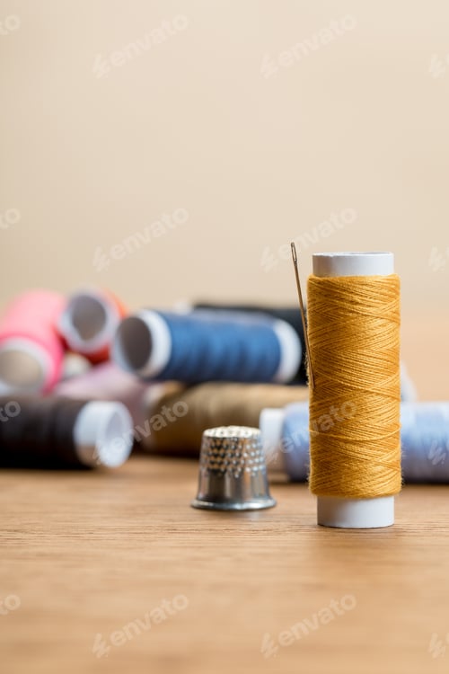 Preview: selective focus of cotton thread coil with needle isolated on beige with copy space