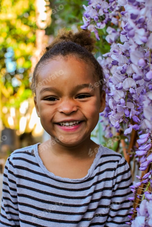 Preview: Portrait of a toddler girl in front of purple wisteria flowers - petals pink mixed race diversity