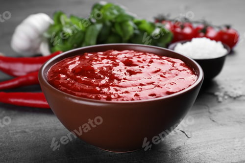 Preview: Bowl of spicy chili sauce on grey table, closeup