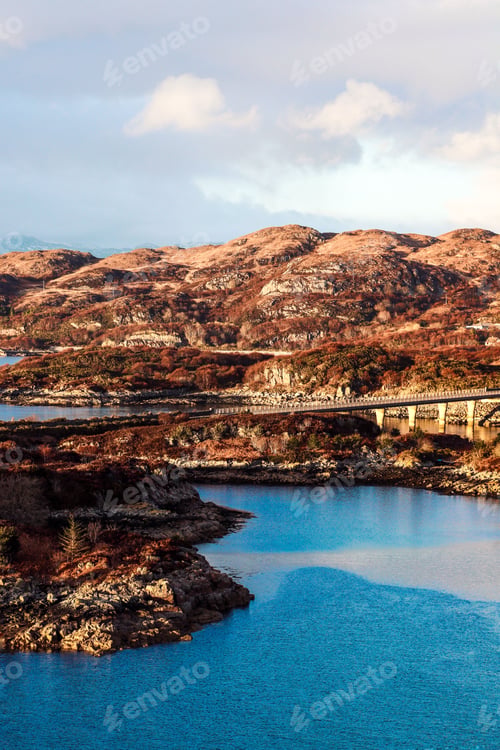 Preview: Expansive roadway along a tranquil body of water near mountains in Kyle of Lochalsh, Scotland, UK