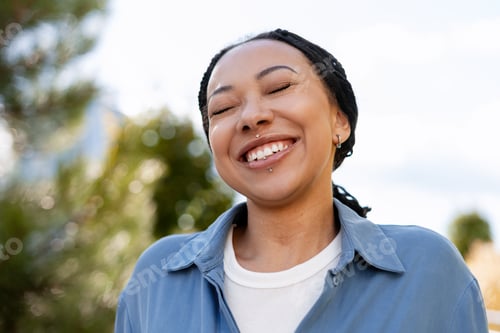 Preview: Young smiling African American woman enjoying freedom and fresh air outdoors with closed eyes
