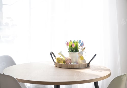 Preview: Easter decoration of colorful eggs, fresh grass in a watering can, easter bunny on a tray on the rou