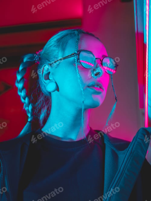 Preview: pretty girl with unusual hairstyle near glowing pink and blue neon lights of the city at night.