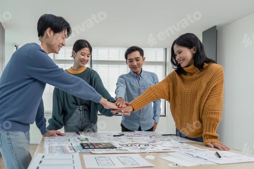 Preview: business team of developers or graphic designers putting their hands together at working table in