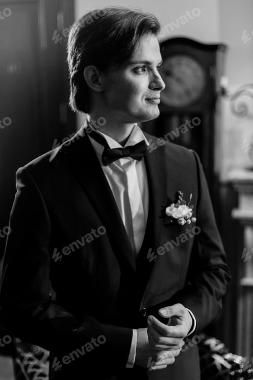 Preview: Stylish groom in bow tie and blue suit getting ready in the morning in hotel