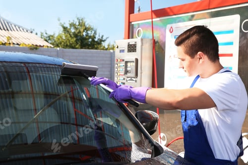 Preview: Worker cleaning automobile windshield with squeegee at car wash