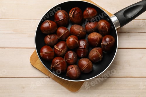 Preview: Roasted edible sweet chestnuts in frying pan on wooden table, top view