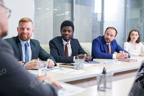 Preview: Several multicultural traders in formalwear listening to coach