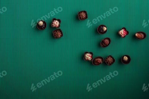 Preview: Flat lay of sweet chocolate candies on green background.