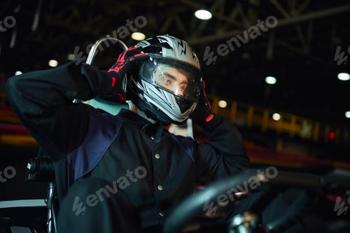 Preview: go kart driver taking off helmet after driving on circuit, speed drive and motorsport concept