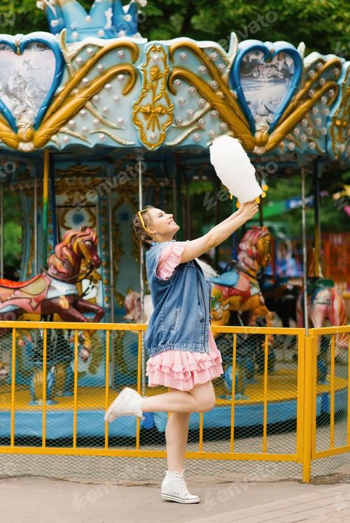 Preview: Young Girl Laughs with Cotton Candy on a Sunny Day at an Amusement Park