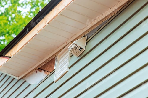 Preview: Ventilation system attached to the exterior wall of a residential building in daylight