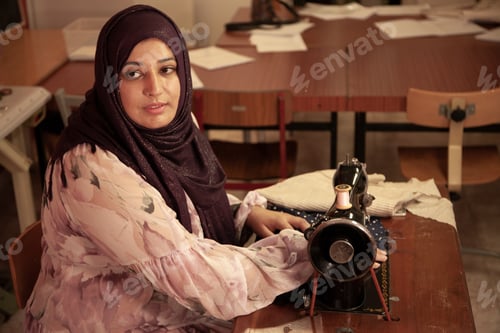 Preview: A seamstress of Arab origin sews a garment on her sewing machine.