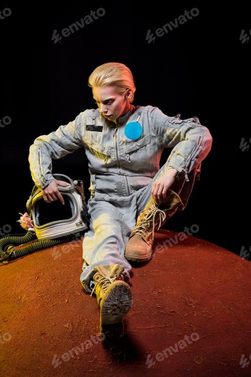 Preview: beautiful astronaut in spacesuit with helmet sitting on planet