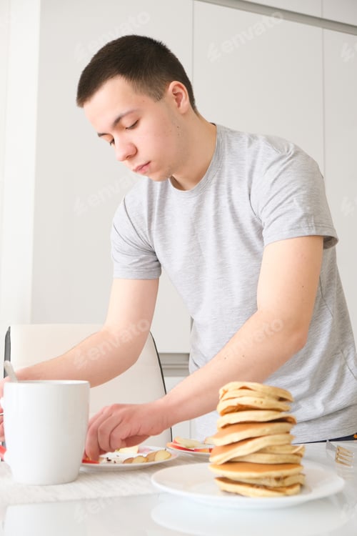 Preview: young guy preparing pancakes for breakfast