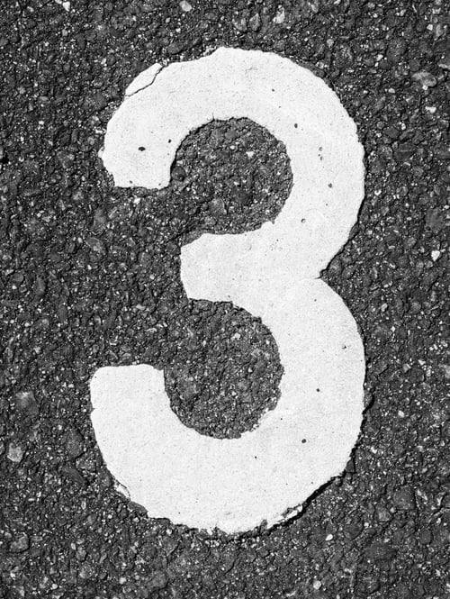 Preview: Vertical shot of a white number three on asphalt ground