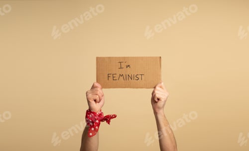 Preview: Hands of a man holding a sign saying " I am feminist" .