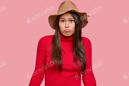 Preview: Uncertain brunette woman has clueless expression, looks in disbelief, purses lips, wears stylish bro