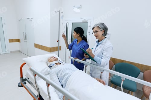 Preview: Doctor examining elderly patient with neck injury lying on medical gurney with cervical collar in