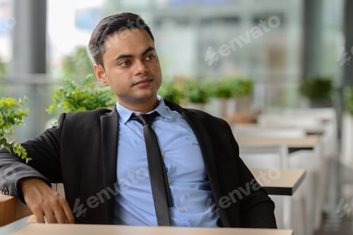 Preview: Young handsome Indian businessman in the city