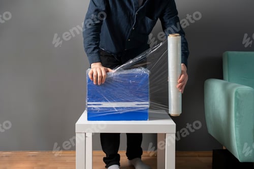 Preview: a person wrapping the package with plastic protective stretch wrap