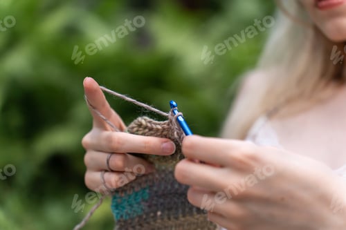 Preview: Close-up of woman hands crocheting against a nature background