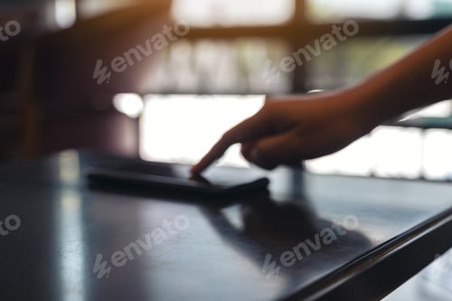 Preview: A finger touching and pointing at mobile phone on the table