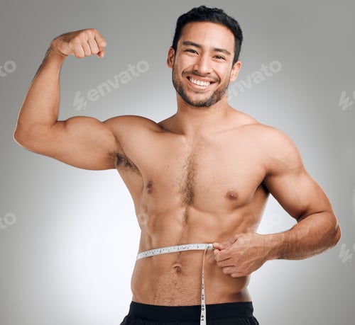 Preview: Studio shot of a man flexing his muscles while measuring his waist