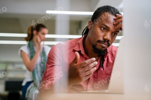 Preview: Stressful job. Stressed african businessman working at laptop, having problem at workplace.