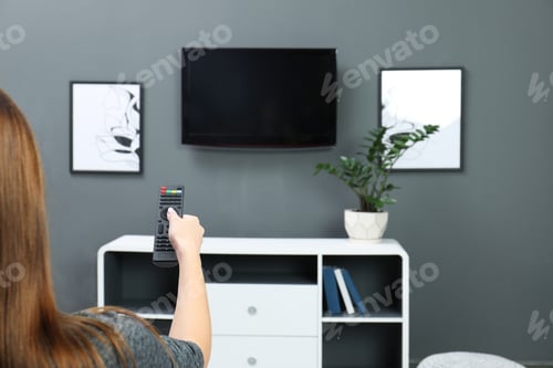 Preview: Woman switching channels on plasma TV with remote control at home