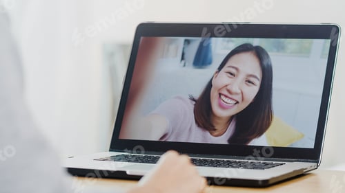 Preview: Asian business female using laptop video call talking with friends while working from home.